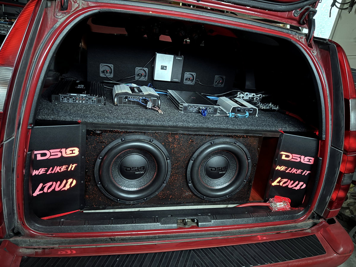 Bagageutrymme med bakbelysta paneler med texten DS18 WE LIKE IT LOUD och subwooferlåda