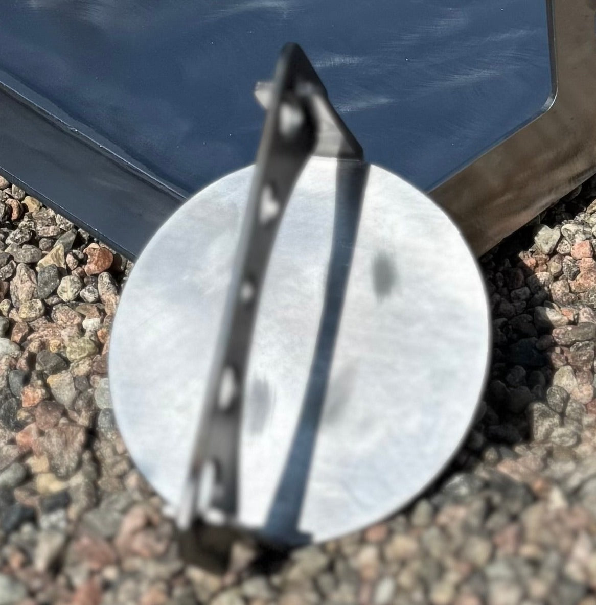 Smashjärn i stål med rund pressplatta och handtag, liggande framför ett stekbord